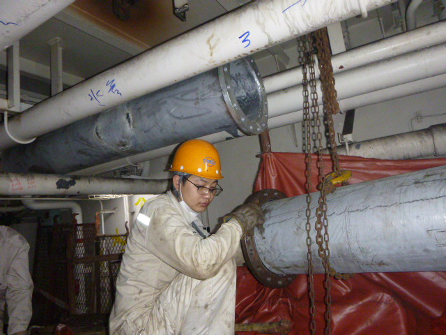 Engineers installing piping in engine room